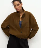 Campera de poliuretano texturizado color marrón, con cuello alto, cierre frontal con botones, mangas largas con puños elásticos y ruedo con elástico.