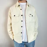 Sobrecamisa de pana en color tostado, con cierre frontal de botones, cuello clásico y dos bolsillos frontales con solapa y botón.