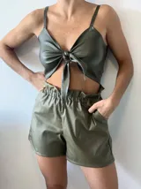 Top negro de cuerina con breteles finos y nudo central que deja ver parte del abdomen.