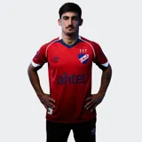 Camiseta de fútbol Umbro del Club Nacional de Football, modelo Away 2026. Diseño en color rojo con detalles en azul y blanco en el cuello y mangas. Incluye logo de Umbro, escudo del club y sponsor Antel en el frente.