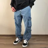 Jean cargo de corte baggy en color azul lavado, con múltiples bolsillos laterales tipo cargo y cierre frontal.