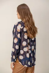 Camisa de manga larga con estampado de leopardo, cuello clásico y cierre frontal de botones. Presenta un corte holgado y puños abotonados.