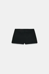 Bermudas negras de tiro medio con cintura ancha, bolsillos delanteros y cierre frontal con cremallera y ganchos metálicos.