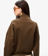 Campera marrón estilo bomber, confeccionada en punto roma, con cuello alto, mangas largas, cierre frontal oculto, bolsillos frontales aplicados y recortes en el pecho.