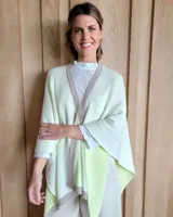 Ruana de tejido de punto en color crema con detalle de estrella grande en color verde lima en la espalda y bordes en tono arena.