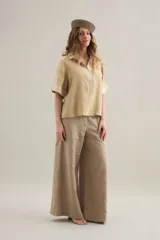 Blusa de lino color beige, de silueta cómoda y relajada, con cuello polo y puños en tono más claro.