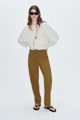 Pantalón de tiro alto con corte recto, cierre frontal con cremallera y botones decorativos en el bajo.