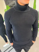Sweater de hilo negro con cuello tortuga, tejido acanalado y mangas raglán.