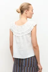Blusa negra estilo bardot con escote de hombros descubiertos, detalles de volados fruncidos en el pecho y diseño sin mangas.
