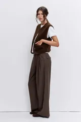 Chaleco de textura tipo corderito en color marrón chocolate, con cuello redondo, cierre frontal con botones y bolsillos laterales.