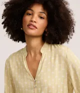 Camisa de viscosa color amarillo, con cuello padre, cierre frontal con botones y mangas largas con puños ajustados. Presenta estampa de follaje y palmeras en tono blanco.