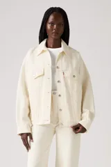 Campera de jean color crema, estilo trucker de los años 90, con cuello clásico, cierre frontal con botones metálicos, bolsillos con solapa en el pecho y corte holgado.