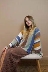 Sweater de algodón tejido a rayas verticales en el cuerpo y horizontales en las mangas. Presenta una mezcla de colores vibrantes como naranja, rosa, verde azulado, marrón, blanco, negro y violeta. Tiene terminaciones en crochet en los puños.