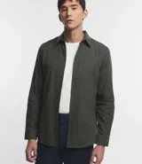 Camisa de manga larga confeccionada en tricolina de algodón, con cuello inglés, cierre frontal de botones y puños abotonados. Diseño liso y versátil.