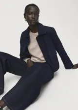 Chaqueta de algodón estilo denim en color azul oscuro, con cuello camisero, bolsillos de parche con solapa en el pecho y cierre frontal con botones.