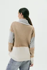 Sweater de lana color beige, gris y blanco, con cuello alto con cierre y detalles de crochet.
