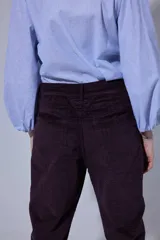 Pantalón de corte recto y tiro medio, confeccionado en tejido con patrón de cuadros oscuros. Presenta bolsillos frontales amplios y terminación con dobladillo en los tobillos.