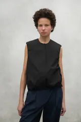 Chaleco negro de corte recto y holgado, con cuello redondo y cierre frontal oculto. Confeccionado en poliéster reciclado, presenta un diseño minimalista y funcional.