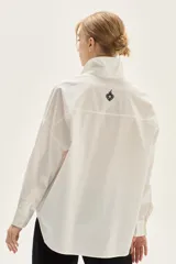 Camisa blanca de corte oversize, confeccionada en algodón, con cuello clásico y cierre frontal de botones. Presenta un bordado de corazones en el pecho.