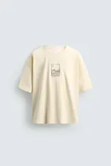 Camiseta de corte relajado color crema, con cuello redondo y manga corta. Presenta un pequeño bordado frontal con diseño de paisaje montañoso en color negro.