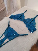 Conjunto de lencería de encaje floral color verde petróleo, compuesto por un corpiño triangular sin aro y una bombacha tipo colaless con tiras laterales ajustables.