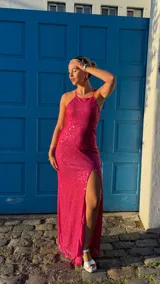 Vestido largo fucsia de lentejuelas con escote halter y tajo lateral.