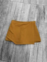 Short pollera color mostaza, de corte mini y diseño cruzado en el frente.