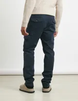 Pantalon cargo de corte recto en color verde militar, confeccionado en sarga de algodón con elastano. Presenta bolsillos laterales con fuelle y tapa, además de bolsillos traseros con cierre de botón.