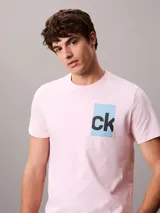 Remera rosada de manga corta con cuello redondo y corte regular, confeccionada en algodón regenerativo. Cuenta con un estampado gráfico en caja de color celeste con el monograma "ck" en negro en el pecho.