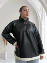 Buzo negro de ecocuero con cuello polo, cierre frontal con cremallera dorada y puños con elástico.