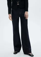 Pantalón de jean de tiro medio color azul oscuro, corte wide leg con cuatro bolsillos y costura ancha en el bajo. Cierre frontal con cremallera y botón.