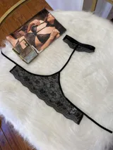 Conjunto de lencería de tres piezas en encaje negro. Incluye bralette con breteles regulables, collarín integrado con cuello ajustable y tanga regulable con corte media less.