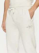 Pantalón de chándal color crema, con cintura elástica ajustable con cordón, puños de canalé, bolsillos laterales y trasero. Presenta el monograma de Calvin Klein bordado en la pierna.