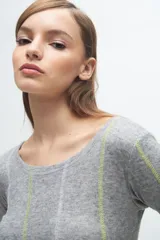 Remera de manga larga en color gris melange, con cuello redondo y costuras decorativas verticales en contraste de color verde lima y blanco.