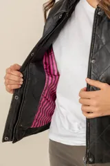 Campera de cuero negro estilo capitoneada, con diseño acolchado de rombos, cuello camisero, cierre frontal con botones a presión y bolsillos laterales.