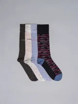 Pack de cuatro pares de medias largas de vestir con diseños variados. Incluyen un par gris oscuro, un par beige, un par celeste y un par negro con rayas horizontales fucsia y blancas. Todos los pares tienen el logo de Calvin Klein.