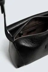 Bolso bandolera negro de piel con textura, cierre de solapa con imán y cremallera. Incluye bolsillo interior con cremallera y bolsillo plano. Asa de hombro ajustable de piel.