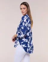 Blusa de gasa de calce suelto y caída ligera, color azul con estampado floral blanco. Presenta escote en V con cuello mao, tabla central, mangas largas regulables con presilla y botón, ruedo redondeado de estilo mullet y espalda con canesú y pliegue central.