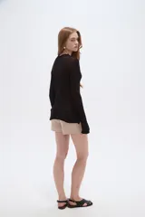 Saco abierto de viscosa color blanco, con cuello en V, lazo para anudar al frente y mangas largas con terminación ondulada.