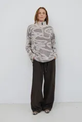 Buzo de tejido de punto con cierre frontal, cuello alto y diseño estampado en tonos beige y marrón.