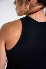Musculosa negra de algodón elastizado, con cuello redondo y corte ajustado al cuerpo. Presenta un estampado pequeño en el centro del pecho.