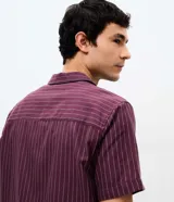 Camisa de manga corta con cuello solapa, cierre frontal de botones y diseño a rayas verticales. Confeccionada en algodón con textura.