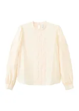 Blusa de color crema con cuello redondo, mangas largas abullonadas y detalles de bordado y puntilla vertical en el frente.