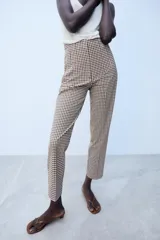 Pantalón de tiro alto con estampado de cuadros vichy en tonos marrón y blanco, con bolsillos laterales de vivo y corte recto.