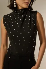 Body sin mangas de algodón, con cuello alto y diseño ajustado al cuerpo, decorado con tachas metálicas plateadas en toda la parte frontal.