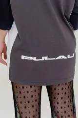 Pantalón acampanado de encaje negro, con estampado de pequeñas flores en relieve. El tejido es semitransparente y cae sobre un calzado tipo zueco negro.