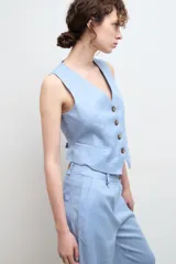 Chaleco sastre de lino con escote en V, cierre frontal con botones y bolsillos delanteros simulados.
