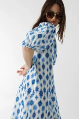 Vestido midi de lino con estampado floral azul y blanco, cuello clásico, mangas abullonadas hasta el codo y cierre frontal con botones de nácar.