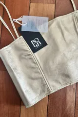 Top clásico color oro suave en cuero ovino folheado, con tirantes finos.