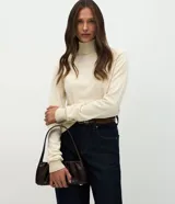 Suéter de punto color crema con cuello alto y mangas largas. Presenta un diseño ajustado al cuerpo con puños acanalados.